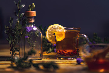 Black tea with lemon in a transparent mug, violet flowers, beaut