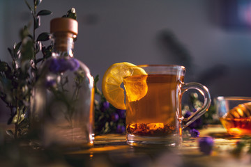 Black tea with lemon in a transparent mug, violet flowers, beaut