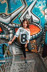 Young woman in front of a graffiti wall