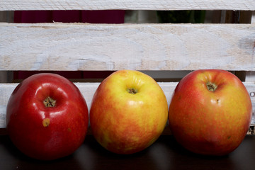 Ripe juicy apples. Against the background of a wooden box.