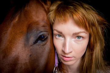 Fototapeta premium Closeup of the head of a horse and a girl in the stable.