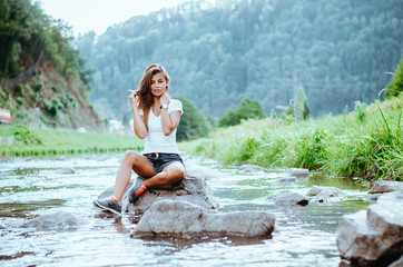 Authentic young woman sitting on a rock in a river