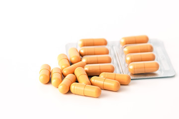 Bright yellow pills and blisters scattered on a white background. Isolated.