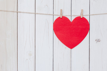 Red heart hanging on white wood  background with copy space.