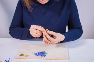 Professional jewelry designer making handmade brooch in traditional russian style with beads in...