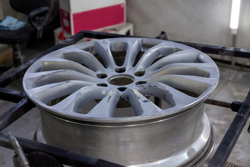 Preparing the surface of the aluminum wheel of the car for subsequent painting in the workshop,...