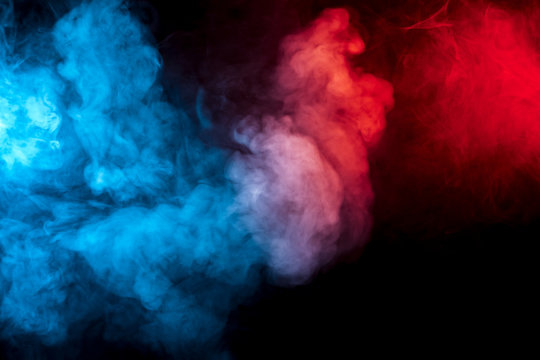 Clouds of isolated colored smoke: blue, red, orange, pink; scrolling on a black background in the dark close up.