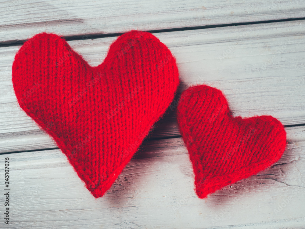 Wall mural knitted red hearts symbolizing love on a wooden white table