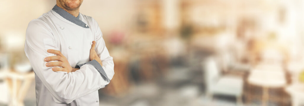 chef standing in restaurant with crossed arms. banner copy space