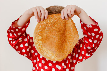 hiding behind the pancakes, the boy covered his face with a large pancake
