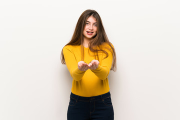 Young woman with yellow sweater holding copyspace imaginary on the palm to insert an ad