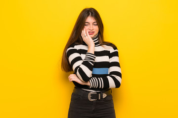 Young woman over yellow wall with toothache