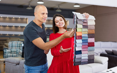 Client consulting with female shopper about choosing furniture in shop