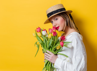woman in white shirt and hat with fresh springtime tulips