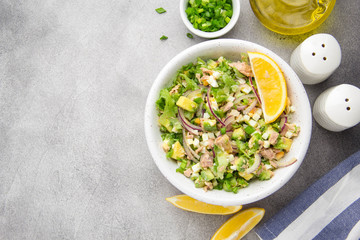 Salad with tuna, avocado, onion, egg and lemon. Spring healthy delicious lunch on light background
