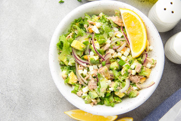 Salad with tuna, avocado, onion, egg and lemon. Spring healthy delicious lunch on light background