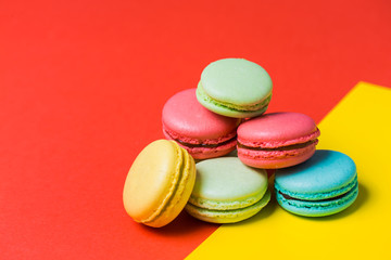 Fototapeta na wymiar Closeup of baked French multicolored macaroons on red and yellow background with copy space