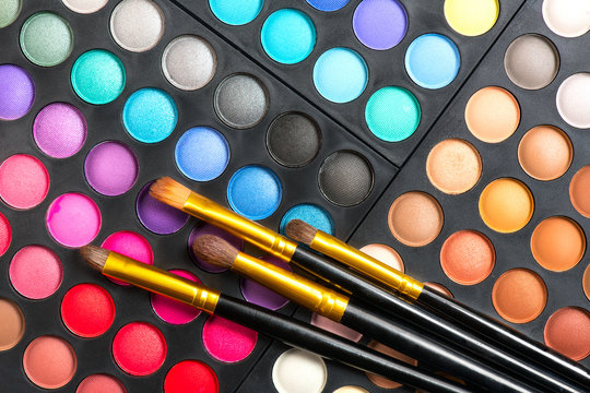 Makeup set. Professional multicolor make up eyeshadows palette and brushes, bright vivid colors and tints of eye shadows set background