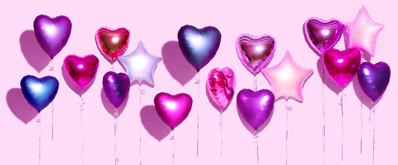 Air balloons. Bunch of purple heart shaped foil balloons, isolated on pink background. Valentine's day background. Wide screen