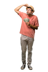Fototapeta premium Man holding many bills having doubts while scratching head on isolated white background