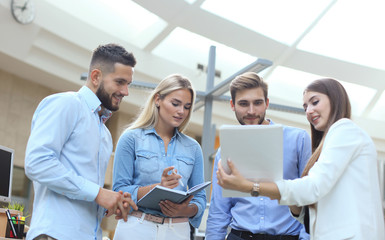 Business discussion. Modern people in casual wear having a brainstorm meeting while standing in the creative office.