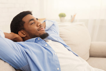 Handsome african-ameriacn man relaxing on sofa at home
