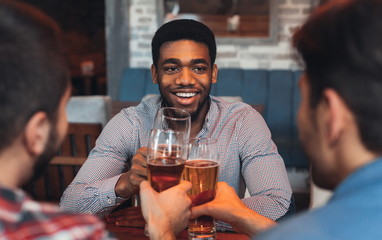 Three men drinking beer, celebrating meeting in bar