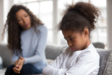 Mom or psychologist talking counseling upset offended african american child girl feels sad...