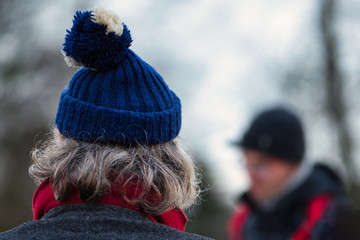 älterer Mann mit grauen Haaren und blauer Pudelmütze im Winter