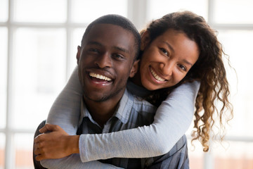 Portrait of happy african american mixed race couple embracing looking at camera, loving husband...
