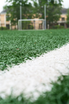 White line on artificial green field against football gate on background, low angle view
