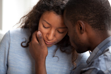 Loving african american husband apologizing comforting sad wife, caring man consoling gently...