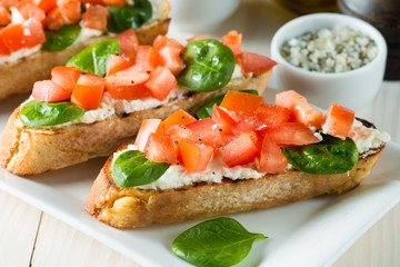 Tomato and cheese fresh made bruschetta. Italian tapas, antipasti with vegetables, herbs and oil on grilled ciabatta and baguette bread. Sandwich.