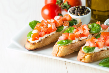 Tomato and cheese fresh made bruschetta. Italian tapas, antipasti with vegetables, herbs and oil on grilled ciabatta and baguette bread. Sandwich.