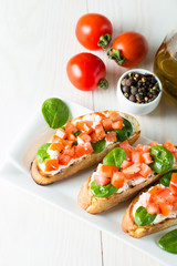 Tomato and cheese fresh made bruschetta. Italian tapas, antipasti with vegetables, herbs and oil on grilled ciabatta and baguette bread. Sandwich.