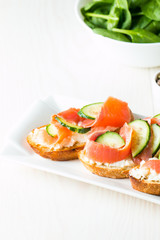Salmon, cucumber and cream cheese bruschetta. Italian tapas, antipasti with vegetables, herbs and oil on grilled ciabatta and baguette bread. Sandwich.