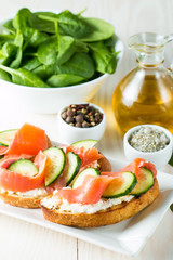 Salmon, cucumber and cream cheese bruschetta. Italian tapas, antipasti with vegetables, herbs and oil on grilled ciabatta and baguette bread. Sandwich.
