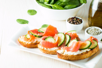 Salmon, cucumber and cream cheese bruschetta. Italian tapas, antipasti with vegetables, herbs and oil on grilled ciabatta and baguette bread. Sandwich.