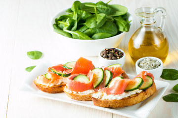 Salmon, cucumber and cream cheese bruschetta. Italian tapas, antipasti with vegetables, herbs and oil on grilled ciabatta and baguette bread. Sandwich.