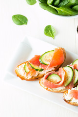 Salmon, cucumber and cream cheese bruschetta. Italian tapas, antipasti with vegetables, herbs and oil on grilled ciabatta and baguette bread. Sandwich.