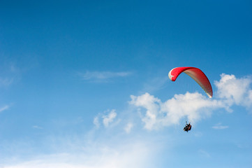Alone paraglider flying in the blue sky against the background of clouds. Paragliding in the sky on a sunny day.