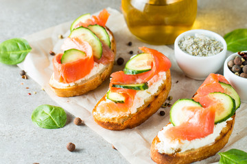 Salmon, cucumber and cream cheese bruschetta. Italian tapas, antipasti with vegetables, herbs and oil on grilled ciabatta and baguette bread. Sandwich.