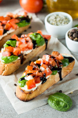 Tomato and cheese fresh made bruschetta. Italian tapas, antipasti with vegetables, herbs and oil on grilled ciabatta and baguette bread. Sandwich.