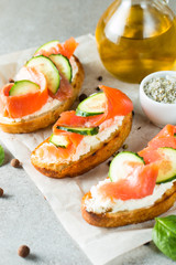 Salmon, cucumber and cream cheese bruschetta. Italian tapas, antipasti with vegetables, herbs and oil on grilled ciabatta and baguette bread. Sandwich.