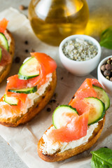 Salmon, cucumber and cream cheese bruschetta. Italian tapas, antipasti with vegetables, herbs and oil on grilled ciabatta and baguette bread. Sandwich.