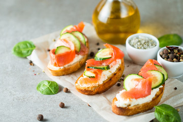 Salmon, cucumber and cream cheese bruschetta. Italian tapas, antipasti with vegetables, herbs and oil on grilled ciabatta and baguette bread. Sandwich.