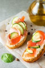 Salmon, cucumber and cream cheese bruschetta. Italian tapas, antipasti with vegetables, herbs and oil on grilled ciabatta and baguette bread. Sandwich.