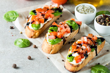 Tomato and cheese fresh made bruschetta. Italian tapas, antipasti with vegetables, herbs and oil on grilled ciabatta and baguette bread. Sandwich.