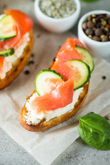 Salmon, cucumber and cream cheese bruschetta. Italian tapas, antipasti with vegetables, herbs and oil on grilled ciabatta and baguette bread. Sandwich.