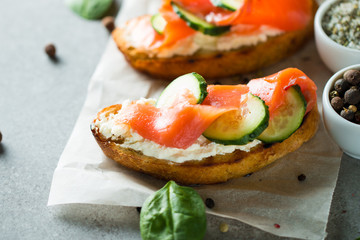 Salmon, cucumber and cream cheese bruschetta. Italian tapas, antipasti with vegetables, herbs and oil on grilled ciabatta and baguette bread. Sandwich.
